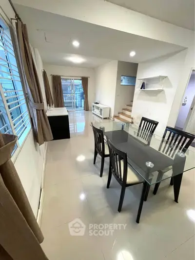 Spacious dining area with glass table and modern decor in a bright, open-plan home.