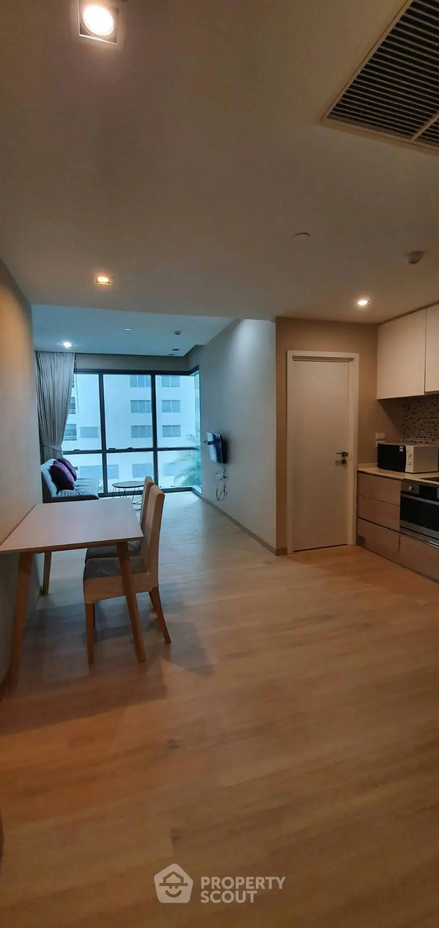 Modern open-plan living area with kitchen and dining space, featuring sleek design and large windows.