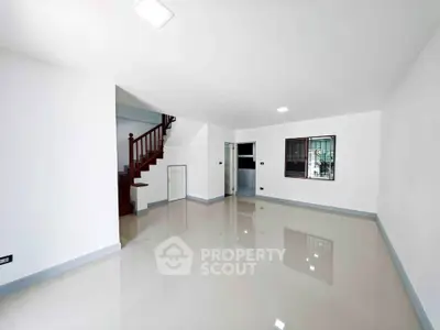 Spacious empty living room with glossy floors and staircase, perfect for customization.