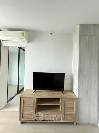 Modern living room with sleek TV stand and air conditioning in a bright apartment.