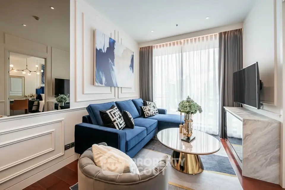 Luxurious modern living room with elegant blue sofa, stylish decor, and large window offering natural light.