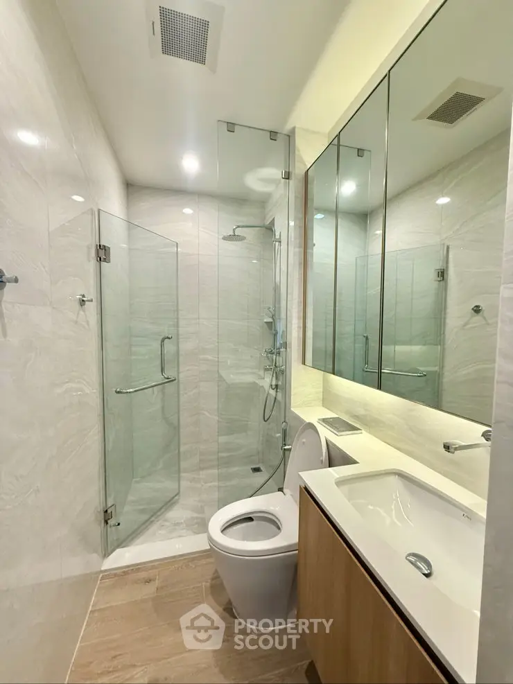 Modern bathroom with glass shower, sleek vanity, and elegant tile design