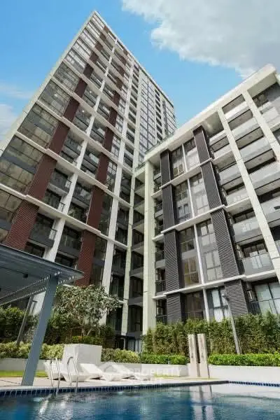 Modern high-rise building with pool and lush greenery, perfect for luxury urban living.