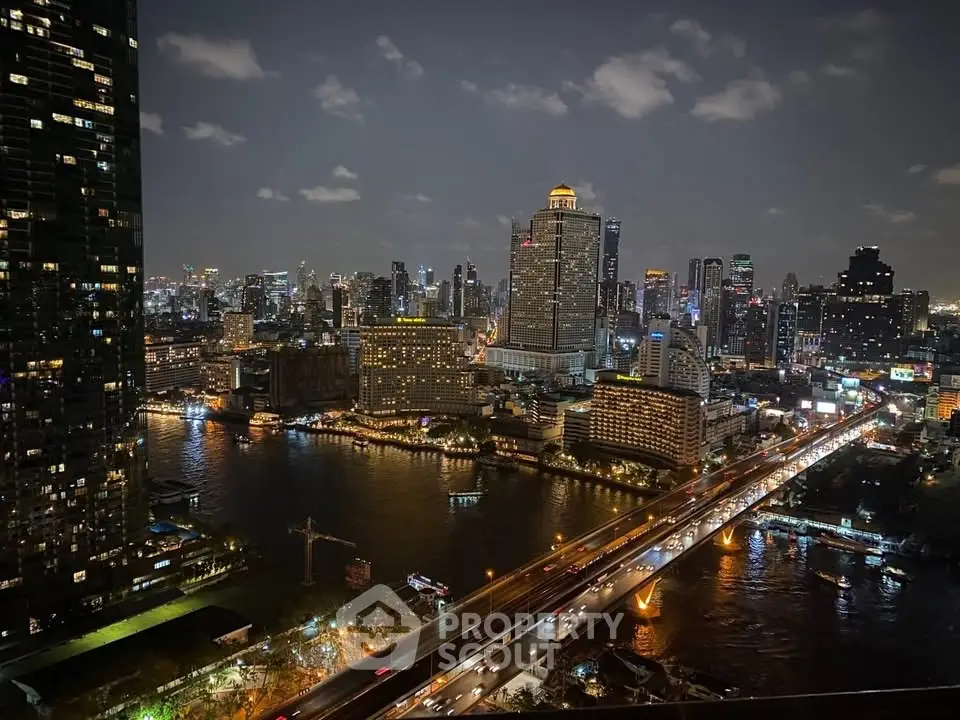 Stunning cityscape view from a high-rise apartment overlooking a vibrant river and illuminated skyline at night.