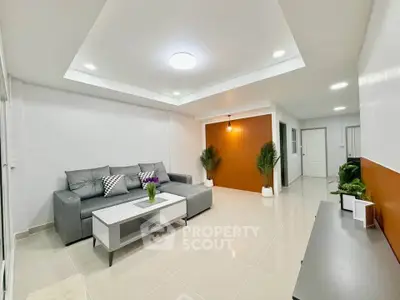 Modern living room with sleek design, featuring a gray sectional sofa, white walls, and stylish lighting.