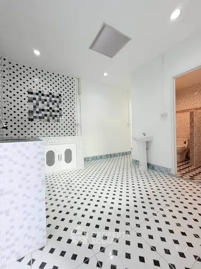 Spacious bathroom with modern black and white tile design and sleek fixtures.