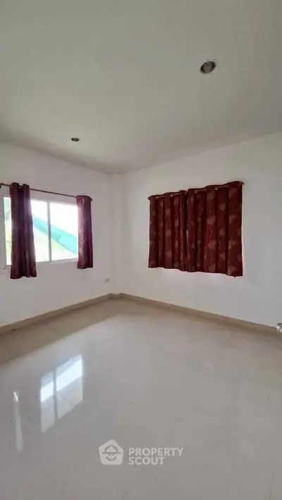 Spacious empty room with large windows and elegant curtains, perfect for customization.