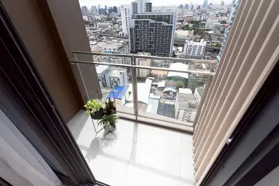 Stunning city view from a modern high-rise balcony with sleek railing and potted plants.