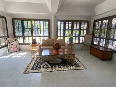 Spacious living room with large windows and elegant decor, perfect for relaxation and entertaining.