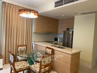 Modern kitchen with wooden cabinets, dining table, and stainless steel appliances in a cozy apartment.