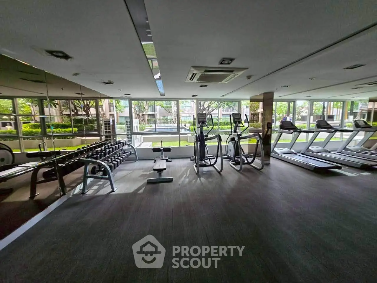 Spacious gym with modern equipment and large windows offering garden views.