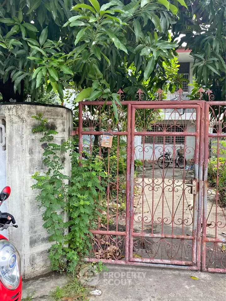Charming gated entrance to a suburban home with lush greenery and rustic appeal.