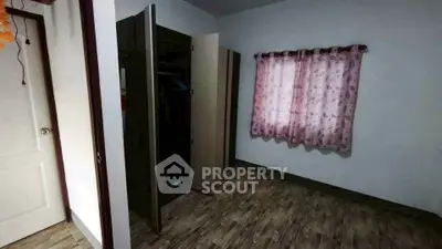 Cozy bedroom with wooden flooring and pink curtains, featuring a built-in wardrobe.
