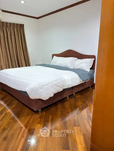 Cozy bedroom with polished wooden floors and elegant curtains, perfect for restful nights.