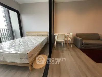 Modern studio apartment with bed, sofa, and dining area, featuring a balcony view.