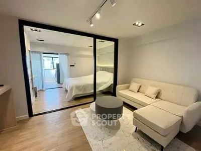 Modern studio apartment with glass partition, cozy living area, and stylish bedroom.