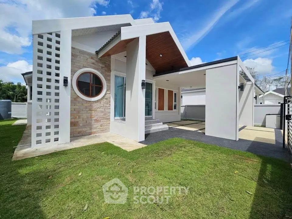 Modern single-story house with unique circular window and spacious lawn.