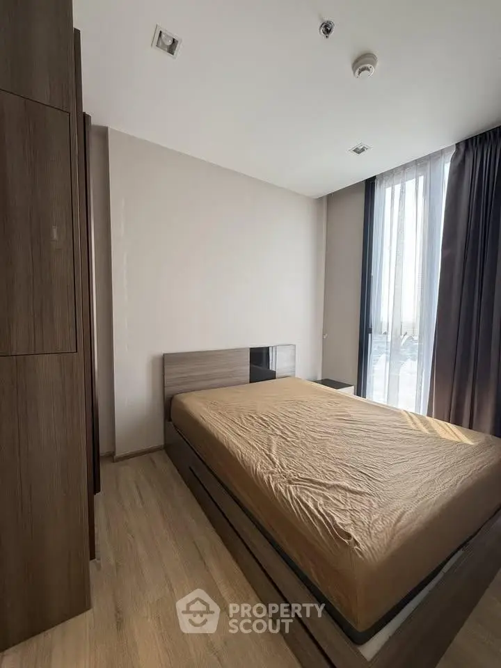 Modern bedroom with wooden flooring and large window for natural light