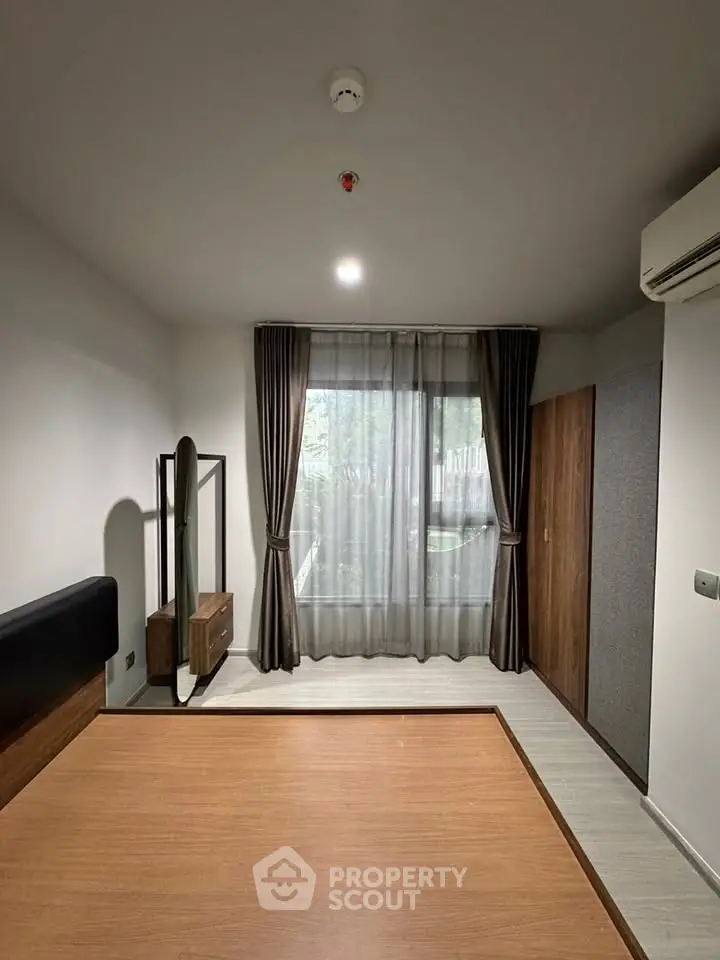 Modern bedroom with large window and stylish furniture, featuring a sleek design and natural light.