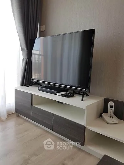 Modern living room with sleek TV stand and large flat-screen TV, elegant curtains, and stylish decor.