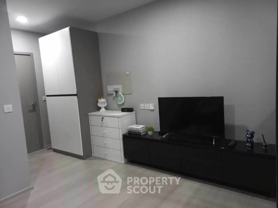 Modern living room with sleek furniture and minimalist decor, featuring a flat-screen TV and ample storage space.