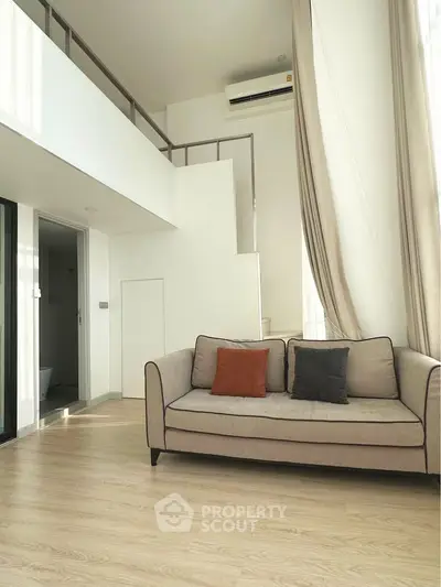 Modern loft-style living room with high ceilings and cozy sofa