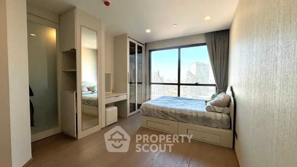 Modern bedroom with city view, featuring sleek furniture and ample natural light.