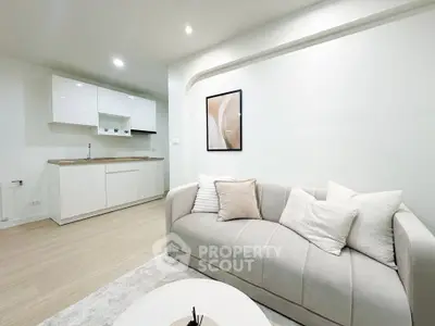 Modern living room with sleek kitchen in open layout, featuring stylish decor and neutral tones.