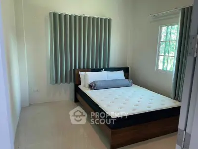 Cozy bedroom with modern bed and large window offering natural light.