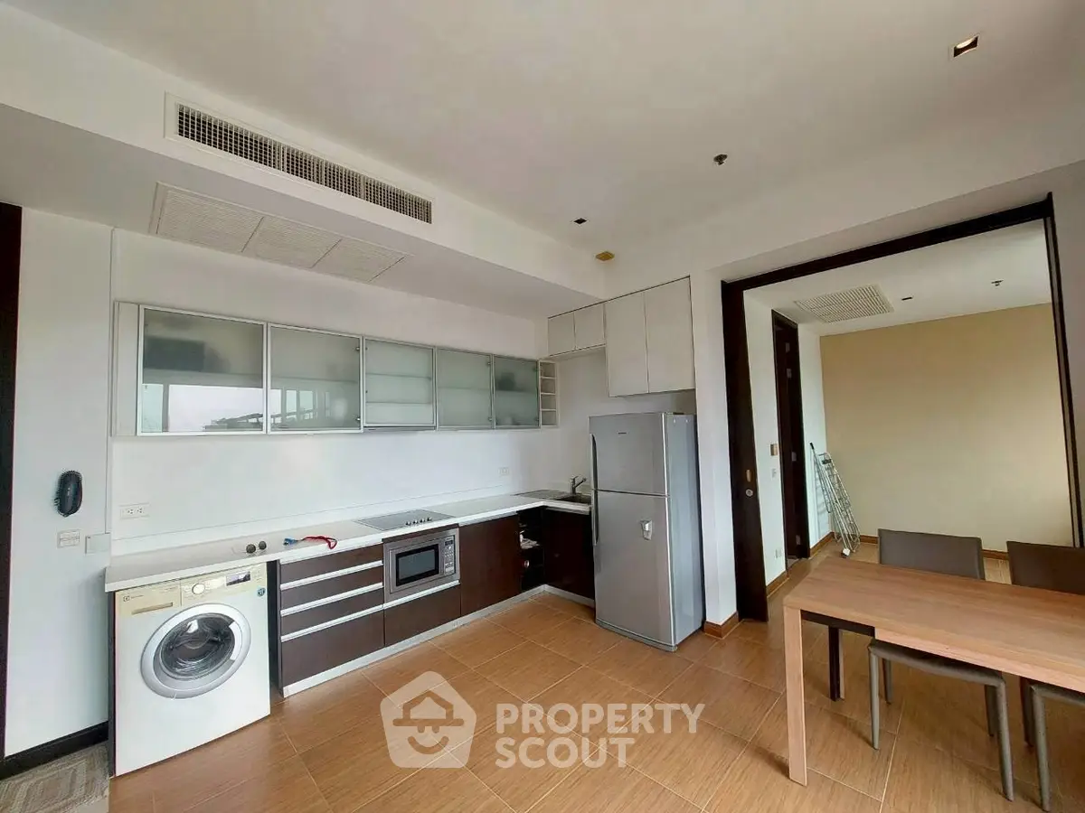 Modern kitchen with sleek cabinets, built-in appliances, and a washing machine in a stylish apartment.