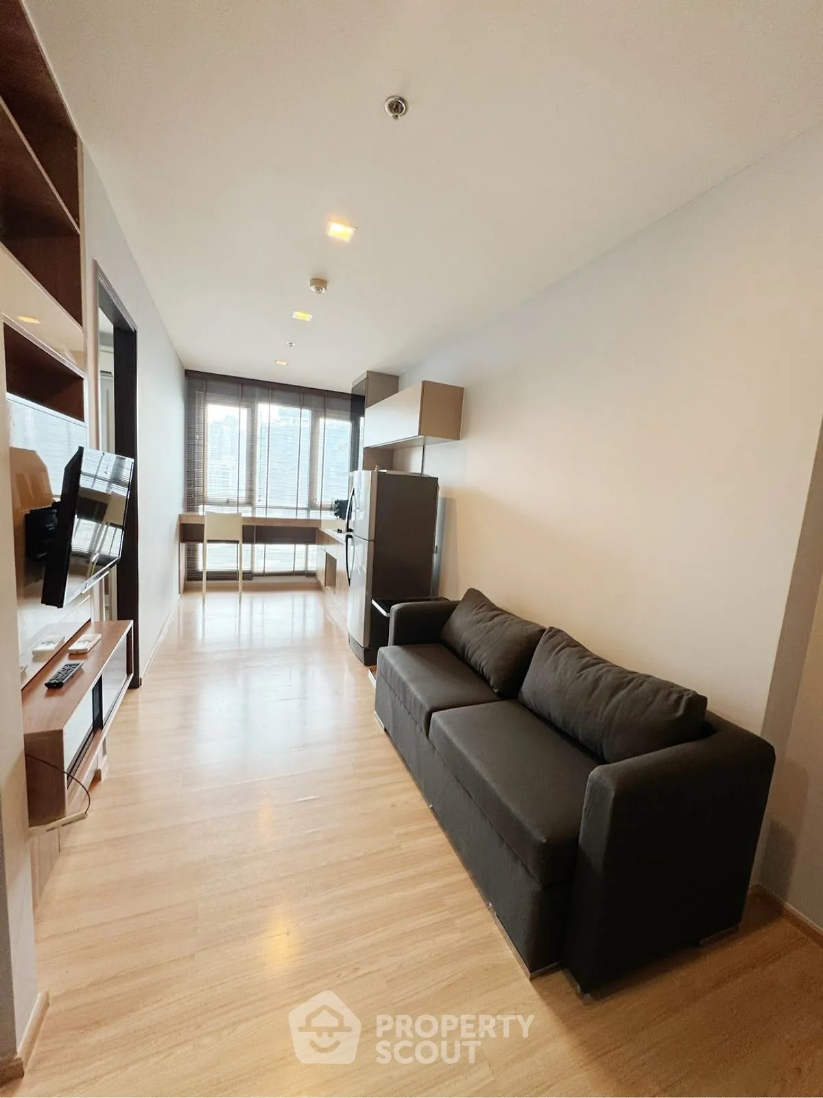 Modern living room with sleek sofa and wall-mounted TV in bright apartment.