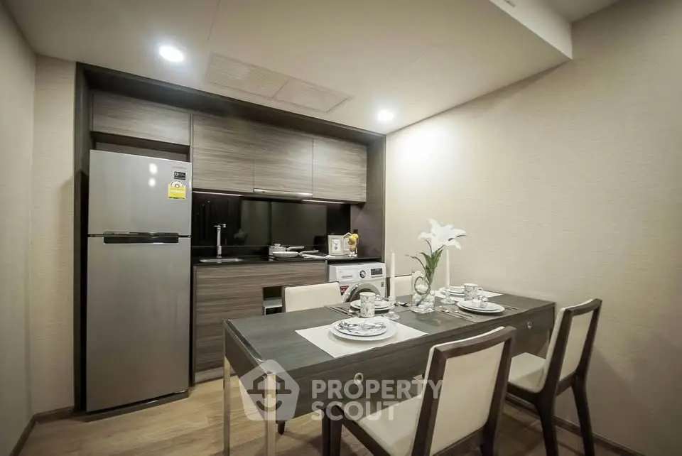 Modern kitchen with dining area featuring sleek appliances and elegant table setting.
