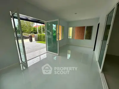 Spacious modern living room with large glass doors opening to a patio, offering seamless indoor-outdoor flow.