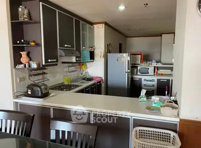 Modern kitchen with sleek cabinetry and stainless steel appliances in a cozy apartment setting.