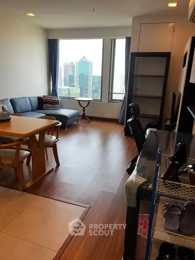 Spacious living room with city view, modern furniture, and wooden flooring in a high-rise apartment.