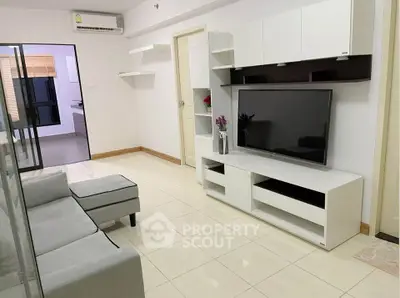 Modern living room with sleek white furniture and large TV unit in a stylish apartment.