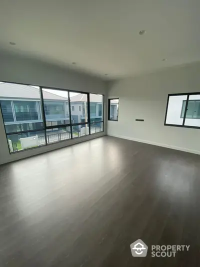 Spacious modern living room with abundant natural light, sleek hardwood floors, and a panoramic view through floor-to-ceiling windows.