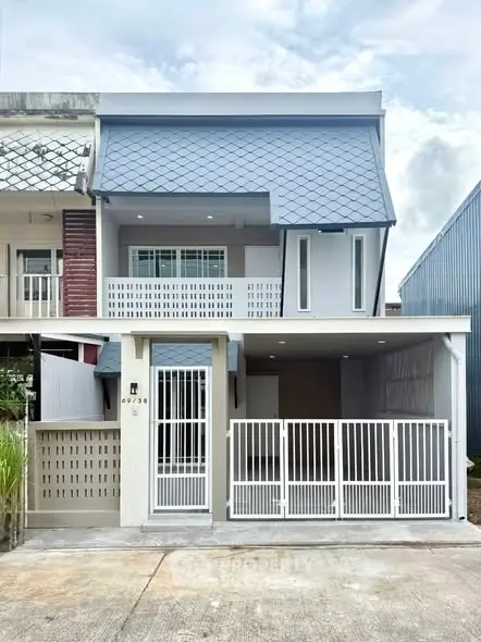 Modern two-story house with unique roof design and gated entrance