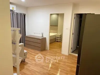 Spacious apartment interior with wooden flooring and modern furniture, featuring a cozy bedroom view.
