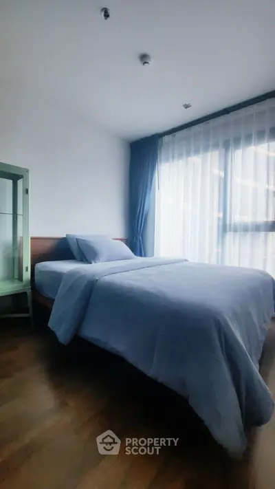 Cozy bedroom with large window and elegant blue curtains, perfect for relaxation.