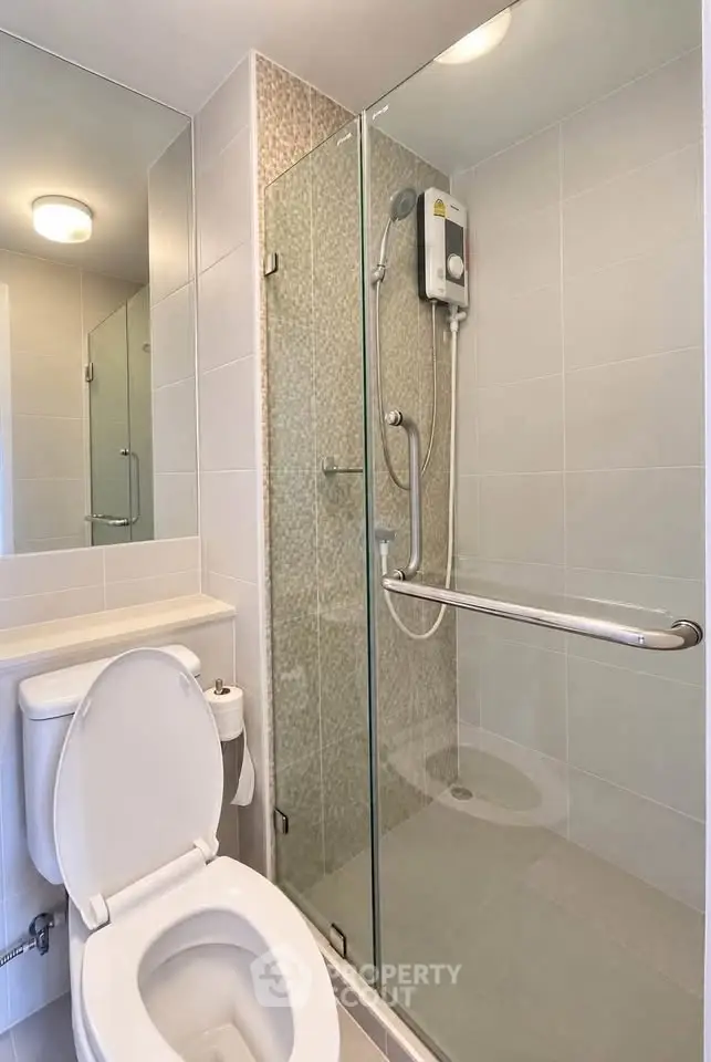Modern bathroom with glass shower enclosure and toilet in sleek design.