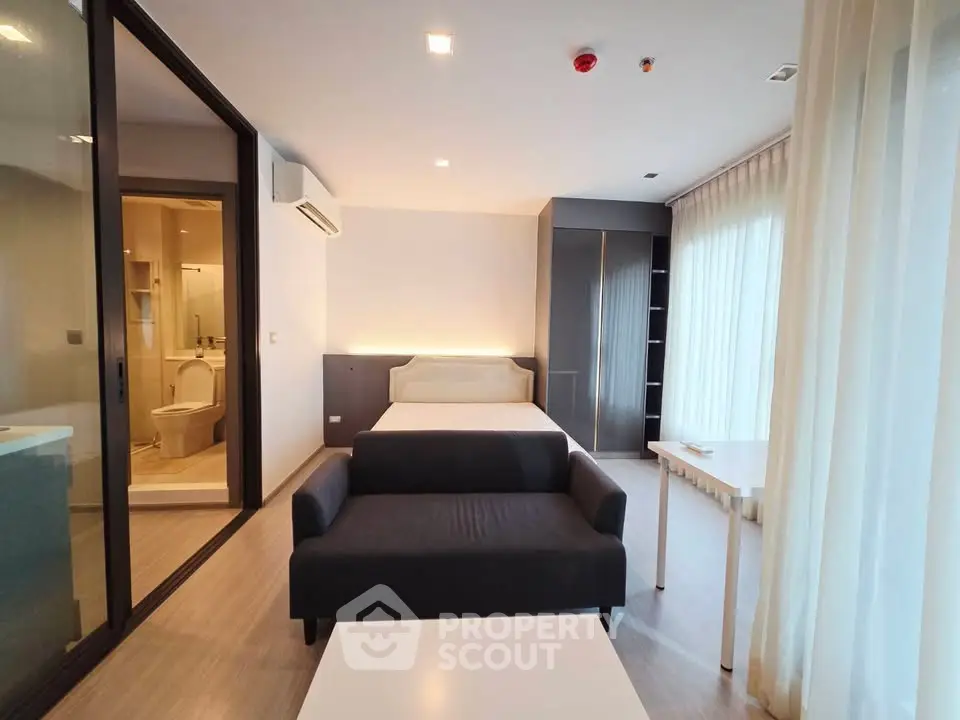 Modern studio apartment with open layout, featuring a cozy living area and adjacent bathroom.