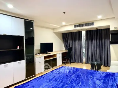 Spacious modern bedroom with sleek furniture and large window view.