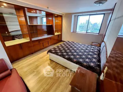 Spacious bedroom with city view, wooden flooring, and built-in storage cabinets.