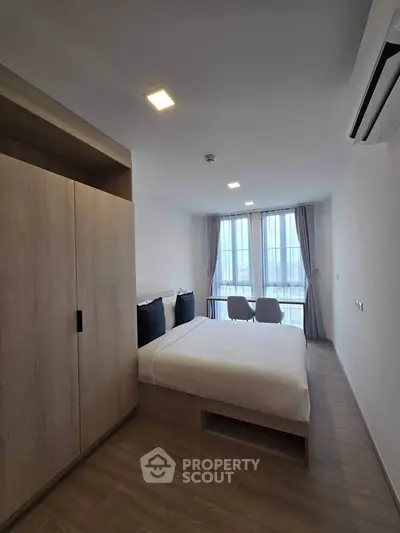 Modern bedroom with large window and stylish decor in a contemporary apartment.