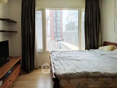 Spacious bedroom with large window offering city view, featuring cozy bed and modern furnishings.