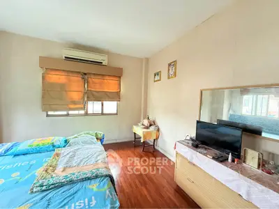 Spacious bedroom with wooden flooring and natural light