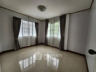 Spacious empty room with large windows and elegant curtains