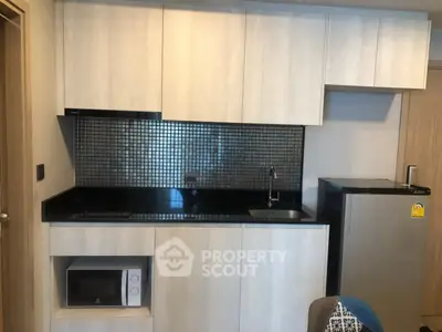 Modern compact kitchen with sleek cabinetry and stainless steel appliances in a stylish apartment.