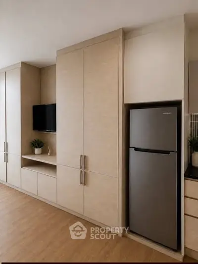 Modern kitchen with sleek cabinetry and stainless steel fridge in stylish apartment.
